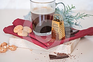 Glass mug of coffy on red napkin and marble coaster, cookies and chocolate