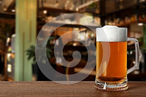Glass mug with cold tasty beer on wooden table in pub, space for text