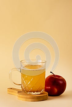 Glass Mug of Fresh Organic Apple Cider with Cinnamon Yellow Background Vertical