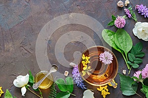 Glass mug of healthy herbal tea, medicinal herbs and small honey jar.