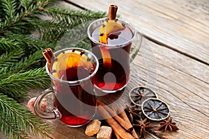 Glass mugs of mulled wine with spices and Christmas tree branches on table. Copy space for text.