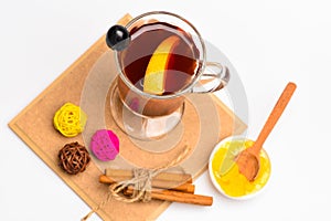 Glass with mulled wine or hot tea with grape, cinnamon and honey on white background, top view. Glass with mulled wine