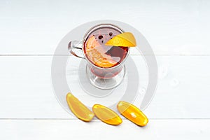 Glass with mulled wine near juicy orange fruit on white background, close up. Cocktail concept. Drink or beverage with