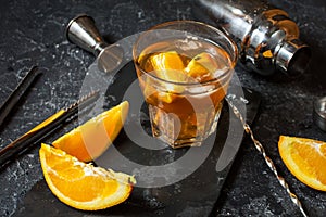 A glass of Negroni cocktail with orange and lemon. Alcoholic drink with rum and vermouth on dark stone table