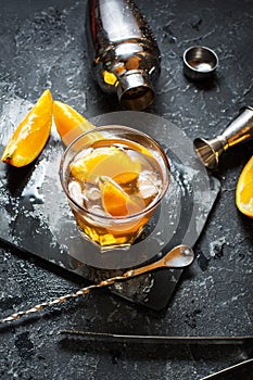 A glass of Negroni cocktail with orange and lemon. Alcoholic drink with rum and vermouth on dark stone table