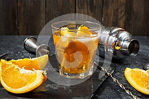 A glass of Negroni cocktail with orange and lemon. Alcoholic drink with rum and vermouth on dark stone table