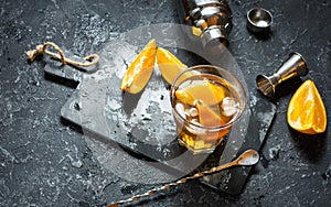 A glass of Negroni cocktail with orange and lemon. Alcoholic drink with rum and vermouth on dark stone table. With space for text