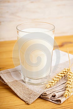 A glass of oat milk, towel on a wooden background. Vertically