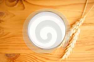 A glass of oat milk on a wooden background. Top view