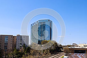 Glass office buildings and apartments along a side a set of railroad tracks with clear blue sky in midtown Atlanta