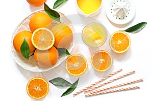 Glass of orange juice with ice cubes and oranges isolated on white background top view.