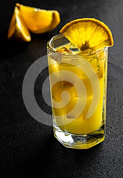 Glass orange juice with ice and slices orange on black background