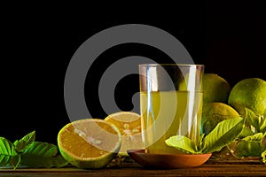 Glass of orange juice and oranges on wooden background