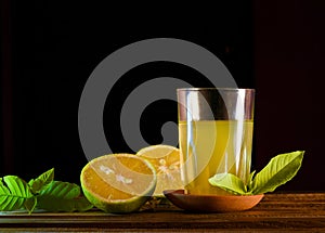 Glass of orange juice and oranges on wooden background