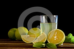 Glass of orange juice and oranges on wooden background