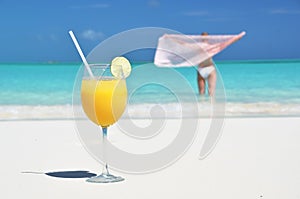 Glass of orange juice on the sandy beach