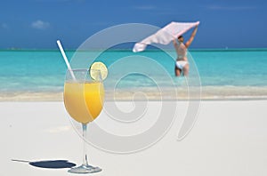 Glass of orange juice on the sandy beach