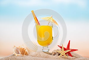 A glass of orange juice, starfish, sea shells and shell in the s