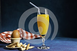 Glass of orange juice with a straw y boiled egg in an egg cup