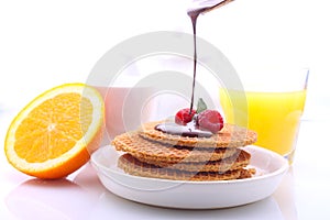 Glass of orange juice and waffles drenched chocolate with raspberries