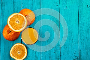 Glass of orange juice on wooden table with fresh sliced fruits of orange.