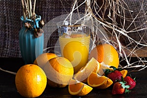 A glass of orange, orange and strawberry juice on a wooden table.