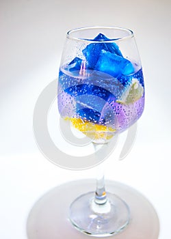 A glass of organic blue Anchana with lemon and ice on a white background.