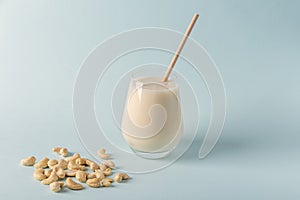 Glass of organic vegan dairy free milk from cashew nuts. Healthy breakfast with vegetarian alternative drink on blue background.