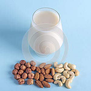Glass of organic vegan dairy free milk from nuts. Healthy breakfast with vegetarian alternative drink. Various types of nuts: