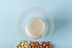 Glass of organic vegan dairy free milk from nuts. Healthy breakfast with vegetarian alternative drink. Various types of nuts: