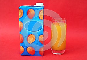 Glass and pack of cold mango juice drink.