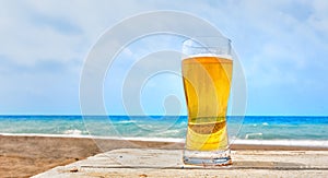Glass of pale golden Pilsener lager at the sea