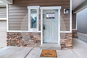 Glass paned front door and sidelight against brick wall and wood siding of home