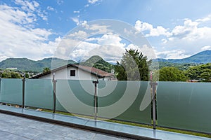 A glass parapet of a modern building balcony overlooking hills