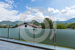A glass parapet of a modern building balcony overlooking hills photo