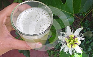 A glass of passion fruit drink with a passin fruit flower