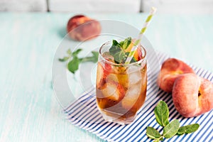 Glass of peach ice tea on wooden table.