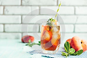 Glass of peach ice tea on wooden table.