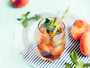 Glass of peach ice tea on wooden table.