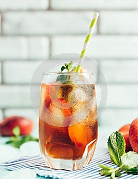 Glass of peach ice tea on wooden table.