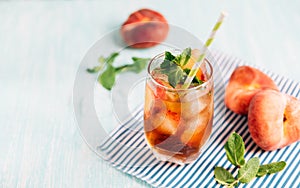 The glass of peach ice tea on wooden table