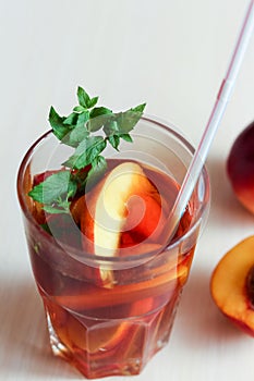 The glass of peach ice tea on wooden table.