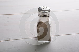 Glass pepper shaker on a wooden table photo