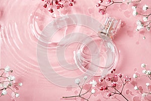 Glass perfume bottle in rose water background. Floral arrangement, splash of water