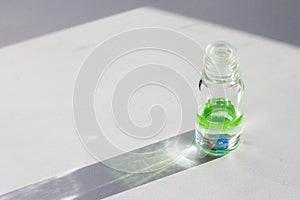 Glass perfume bottles with green liquid on a white background in sunshine