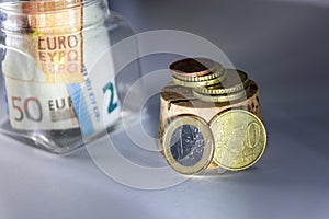 Glass piggy bank with european bank notes and euro coins show savings for travelling, holidays, private investment and cash