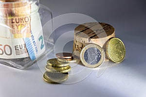 Glass piggy bank with european bank notes and euro coins show savings for travelling, holidays, private investment and cash