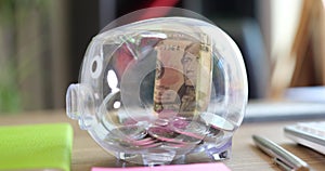 Glass piggy bank is refilled with coins and dollar bills