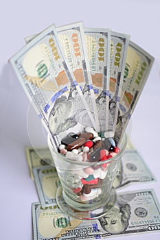 Glass with pills and dollars banknotes.