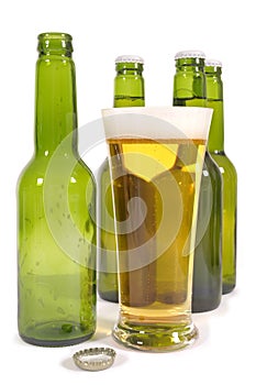 Glass of pilsner lager beer with empty bottles isolated on white background